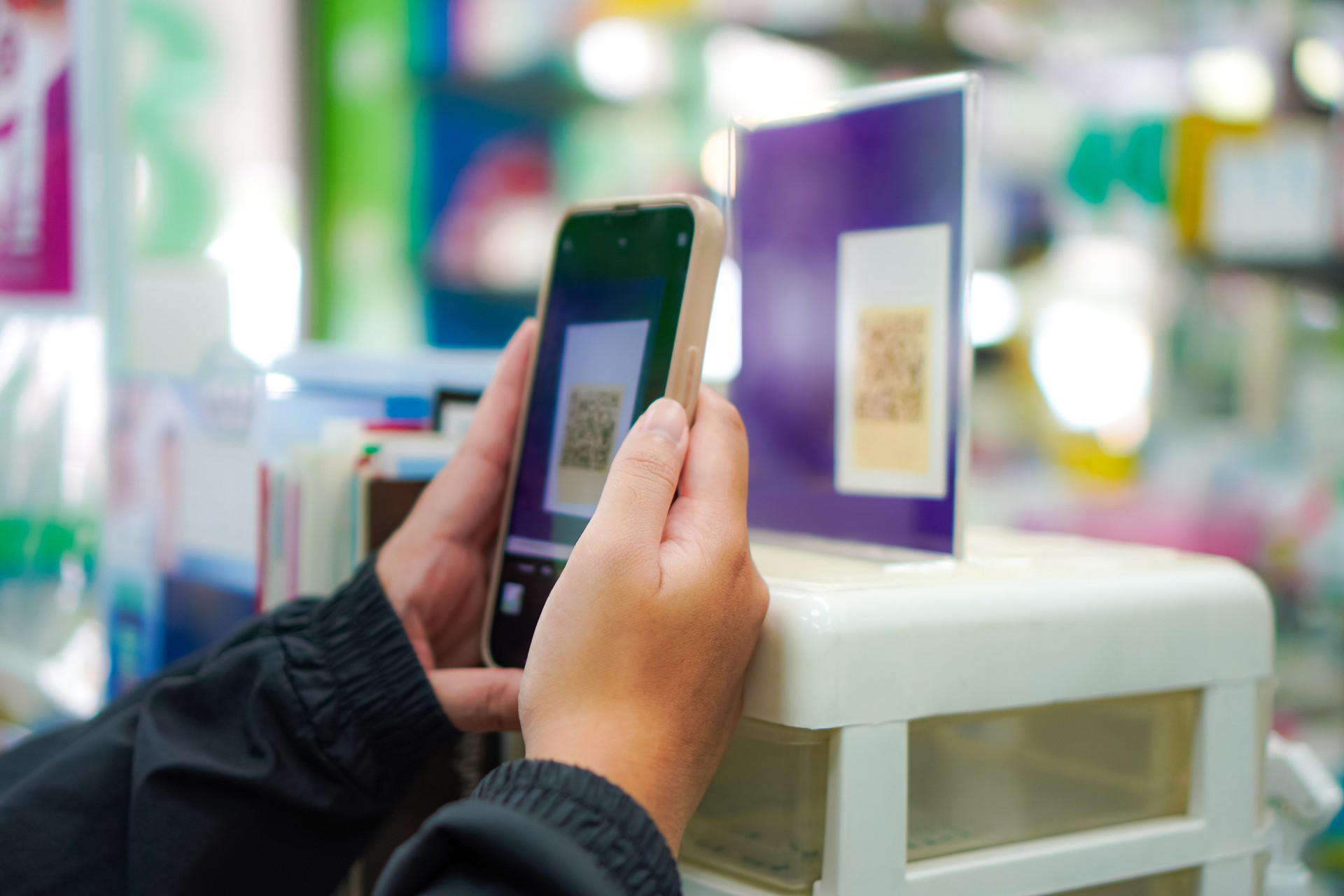 Image of people using smartphones to scan QR codes to pay for products in a pharmacy, Chiang Mai, Thailand.